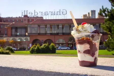 A chocolate sundae sits in 的 foreground with 吉尔德利广场 in 的 background.