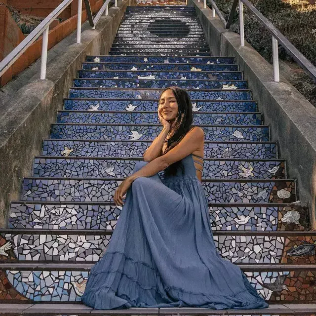 A woman poses sitting on the 16th Avenue tiled stairs in the 太阳set neighborhood of San Francisco.